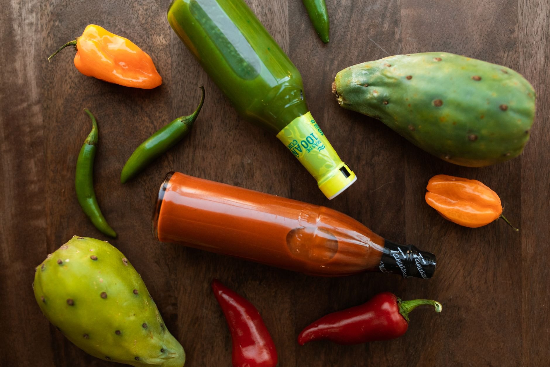 Vibrant display of hot sauces and peppers on a wooden surface